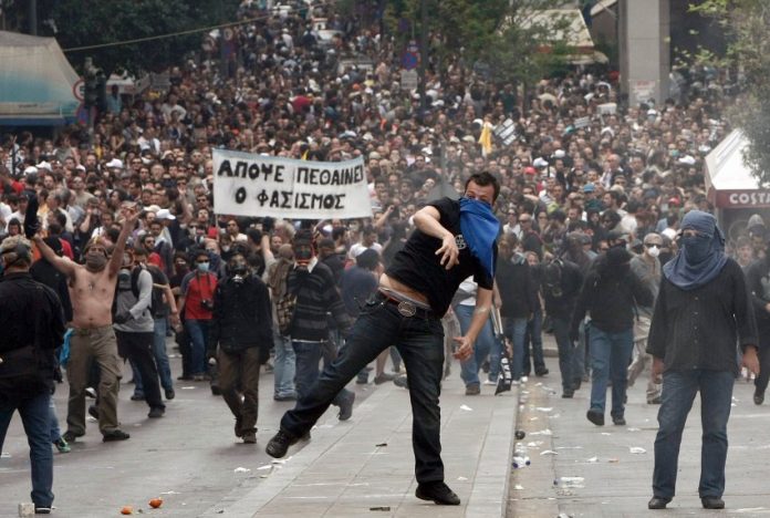 Demonstrators hurl projictiles at riot police during nationwide strike over austerity measures in Athens